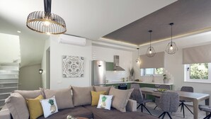 A modern living room with a sectional sofa, a dining table, and a kitchen in the background.