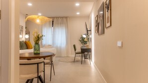 A modern living room with a dining area, featuring a round table, chairs, a sofa, and a decorative plant.