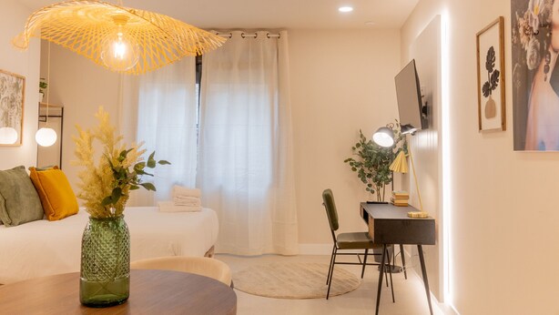 A modern bedroom with a bed, a desk, and a dining table.