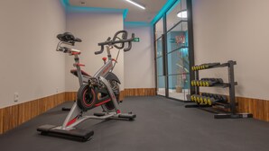 A gym with stationary bikes, a treadmill, and a rack of dumbbells.