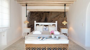 A bed with a white headboard, two bedside tables, a wicker footboard, a magazine, a tray with cups, and a vase with flowers. - Topos Exclusive Mykonos  (Mykonos)