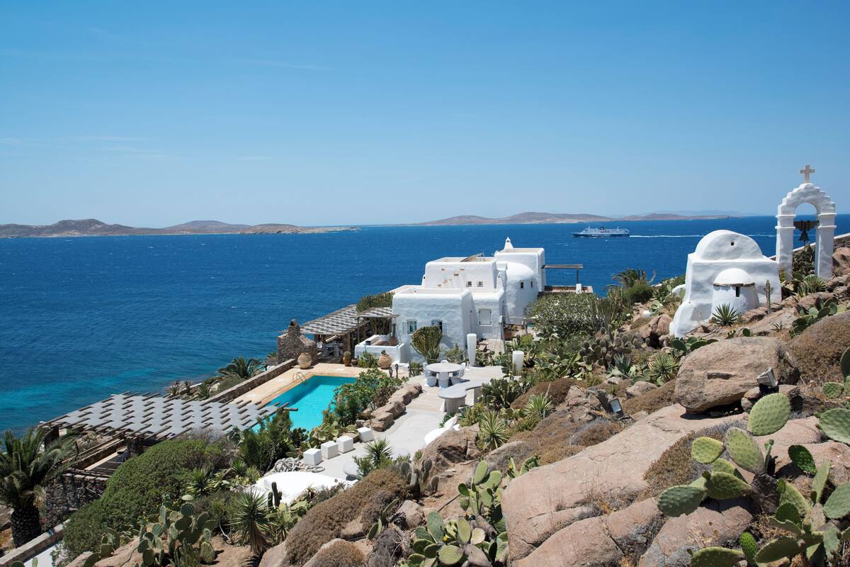Un bâtiment blanc doté d’une piscine, entouré de cactus et de rochers, et offrant une vue sur la mer.
