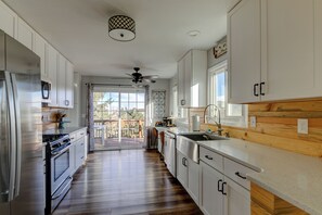 Una cocina moderna con armarios blancos, electrodomésticos de acero inoxidable y una pared de acento de madera.