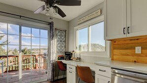 A kitchen with a view of a deck, a ceiling fan, and a window with a sign above it.