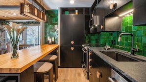 A modern kitchen with a wooden countertop, black cabinets, and a green-tiled backsplash.