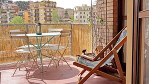 Ein Balkon mit Tisch und Stühlen, einer Liege und Blick auf die Stadt.