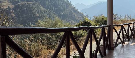 A wooden deck with a railing overlooking a mountainous landscape.