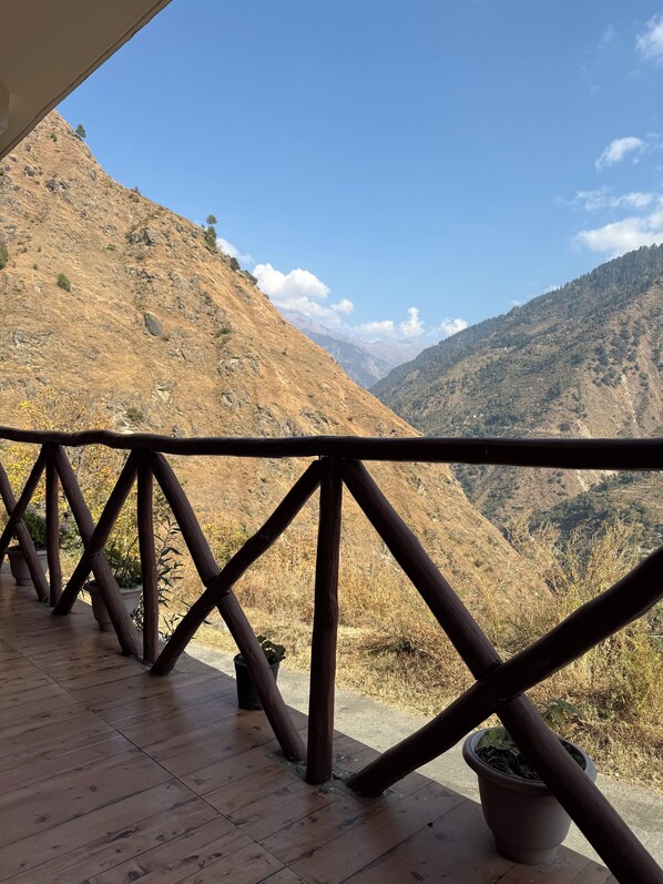 Una terraza de madera con barandilla que da a un paisaje montañoso.