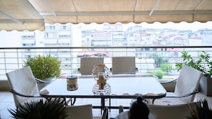 Un balcon avec une table en verre, des chaises et des plantes en pot.