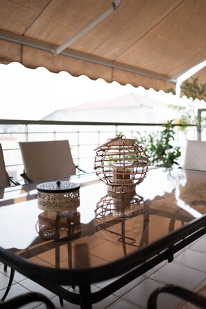 A glass-top table with a woven candle holder and a patterned container. - Home Sweet Home Trikala Town (Trikala)