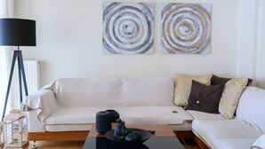 Un salon moderne avec un canapé, une table basse et des œuvres d’art abstraites accrochées au mur.