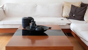Un salon moderne avec une table basse en bois, un canapé blanc et deux tableaux abstraits accrochés au mur.