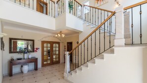 A spacious foyer with a staircase leading to an upper floor, a console table with decorative items, and a large mirror above it. - Villa Montemar, a 4 bedroom Self Check-in Villa walking distance to Carvoeiro (Carvoeiro)