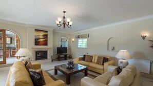 A living room with a fireplace, a television, and a chandelier. - Villa Montemar, a 4 bedroom Self Check-in Villa walking distance to Carvoeiro (Carvoeiro)