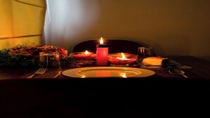 A dimly lit dining table with candles, a plate, cutlery, and a glass of water.