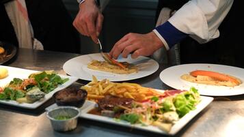 Uma mesa de jantar com diversos pratos, incluindo uma salada, batatas fritas e um bife.