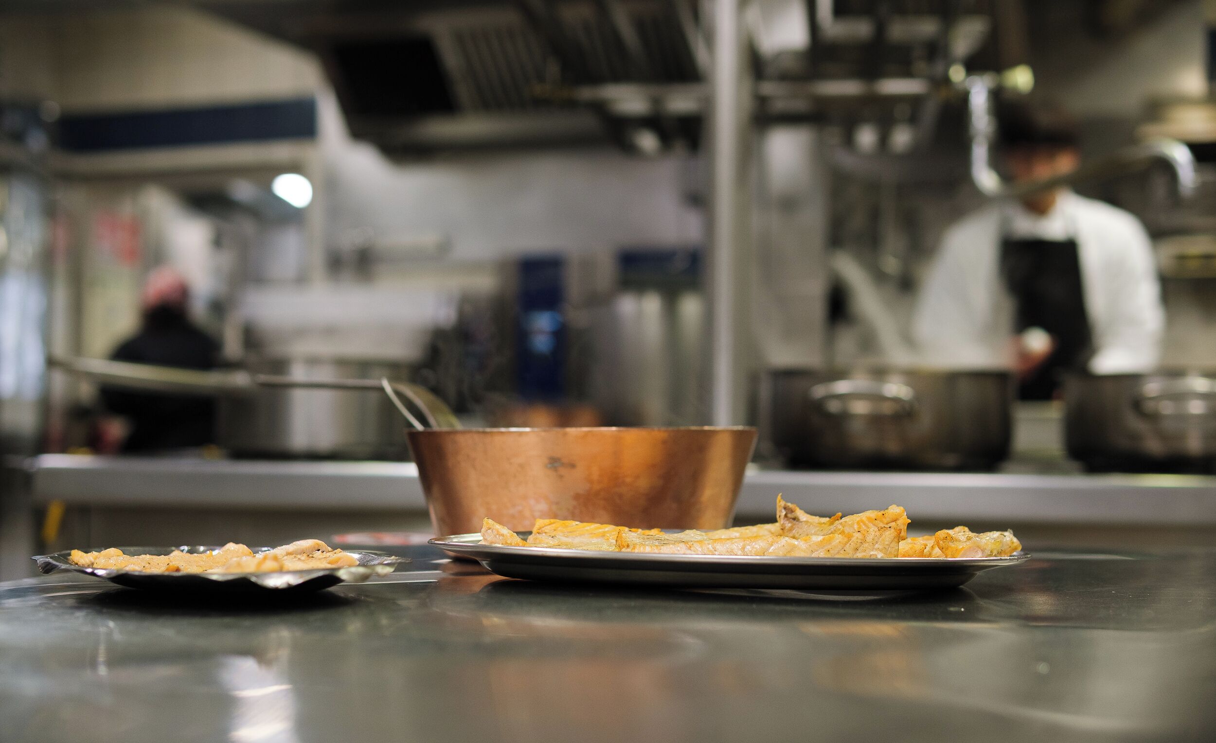 Un plan de travail de cuisine avec une casserole en cuivre et des assiettes remplies de nourriture.