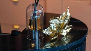 A dark blue, ribbed table with a glass container holding a liquid and two black sticks, and a decorative golden leaf on the table.