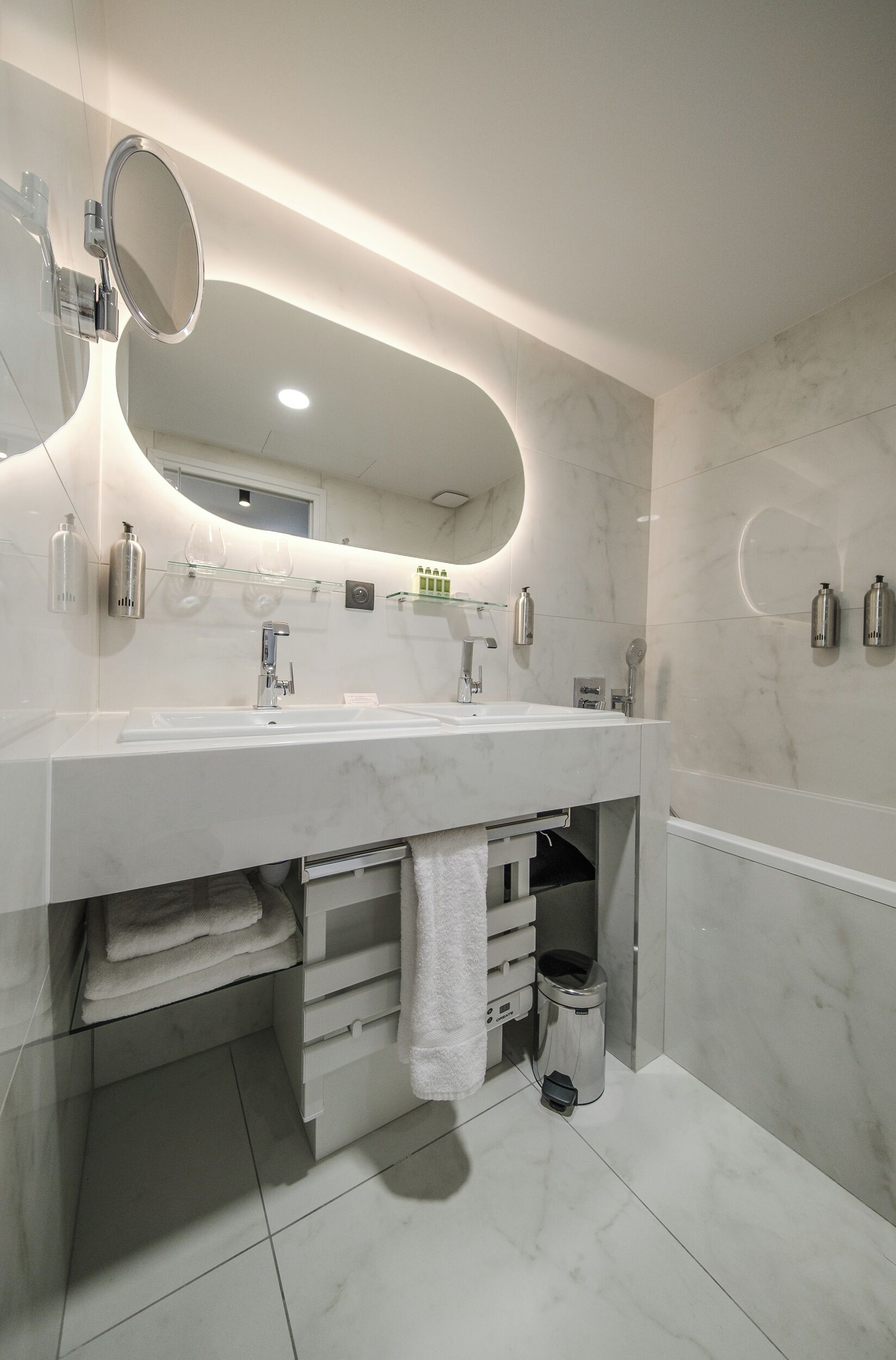 Uma casa de banho moderna com um espelho grande, lavatório e porta-toalhas.