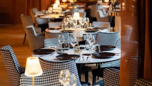 A restaurant with checkered chairs and tables set for dining, featuring clear glassware and table settings. - Hôtel Le Regina (Le Puy-en-Velay)