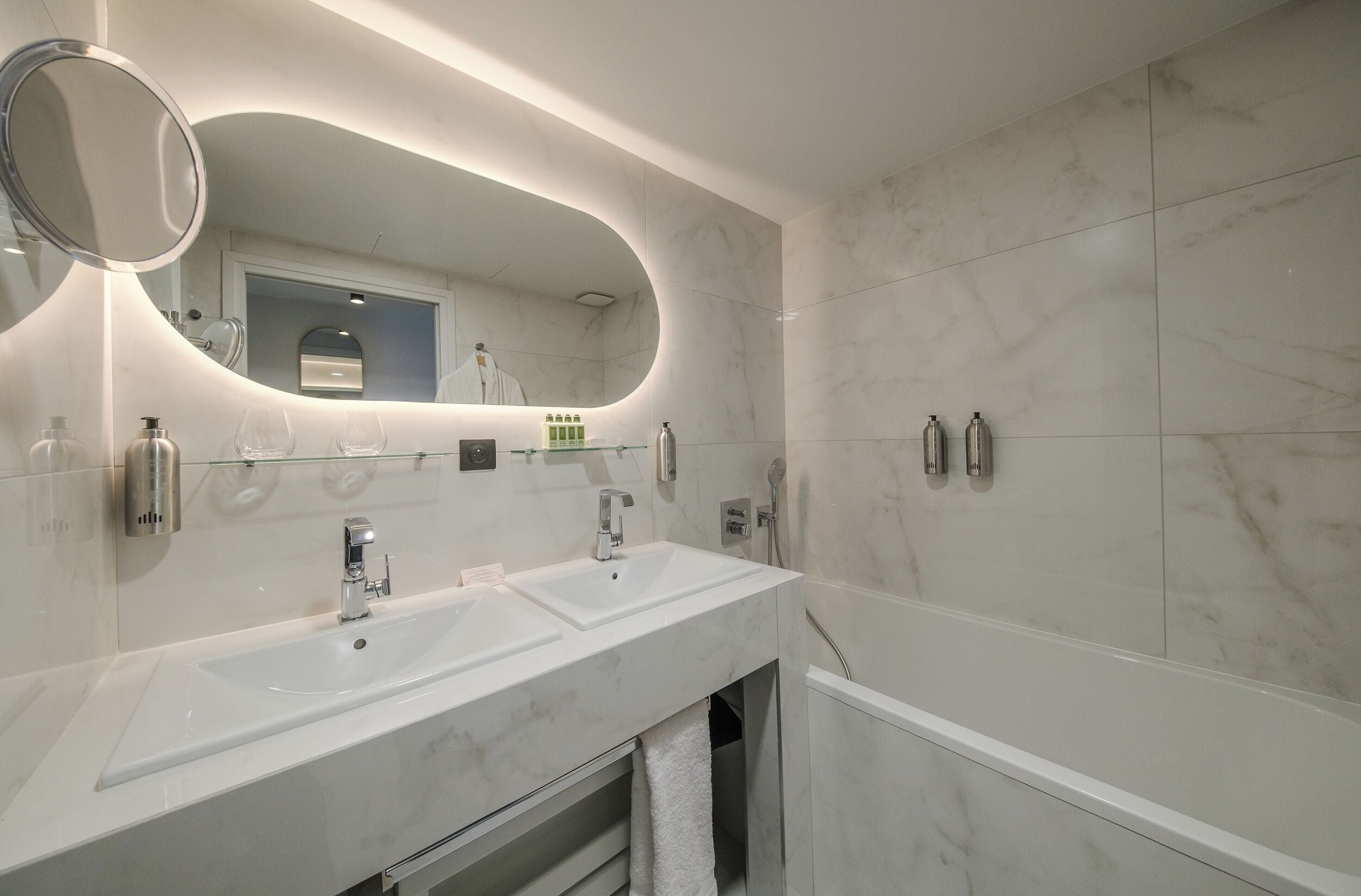 Un baño moderno con dos lavamanos, un espejo grande y una zona de ducha.