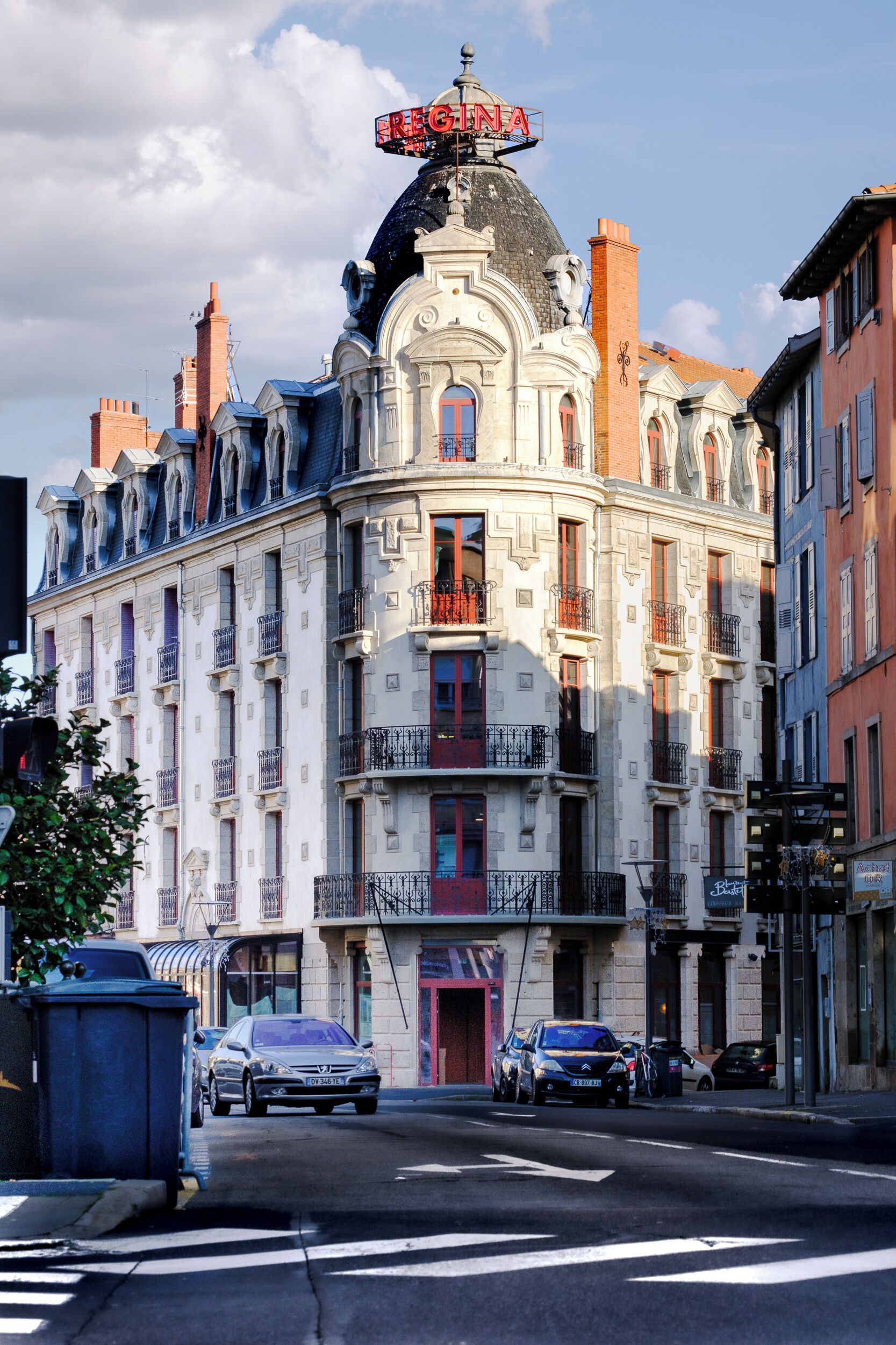 Un edificio histórico con arquitectura ornamentada, varios balcones y un cartel llamativo.