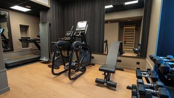 A gym with cardio equipment, weight benches, and dumbbells.