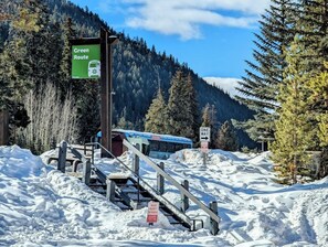 A snowy mountain area with a green sign indicating a 'Green Route' and a 'Free Bus' sign. There is a 'One Way' sign and a 'Private Property No Parking' sign. - Key Condo 2967d (Keystone)
