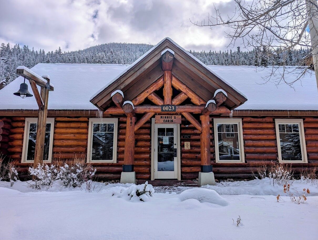 A log cabin with a sign reading "Minnie’s Cabin" and the number "0023" above the door.