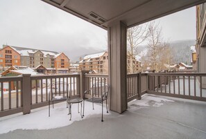A balcony with metal chairs and a view of multi-story buildings with snow on the roofs. - Expedition Station 8572 (Keystone)