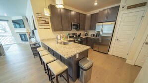 A modern kitchen with dark wood cabinets, stainless steel appliances, and a granite countertop. - Clearwater Lofts Bldg 1 204 (Keystone)