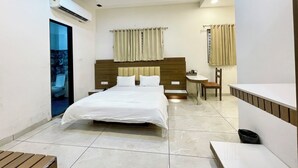 Una habitación de hotel moderna con una cama grande, una mesita de noche, una silla, una pequeña mesa y un lavamanos integrado.