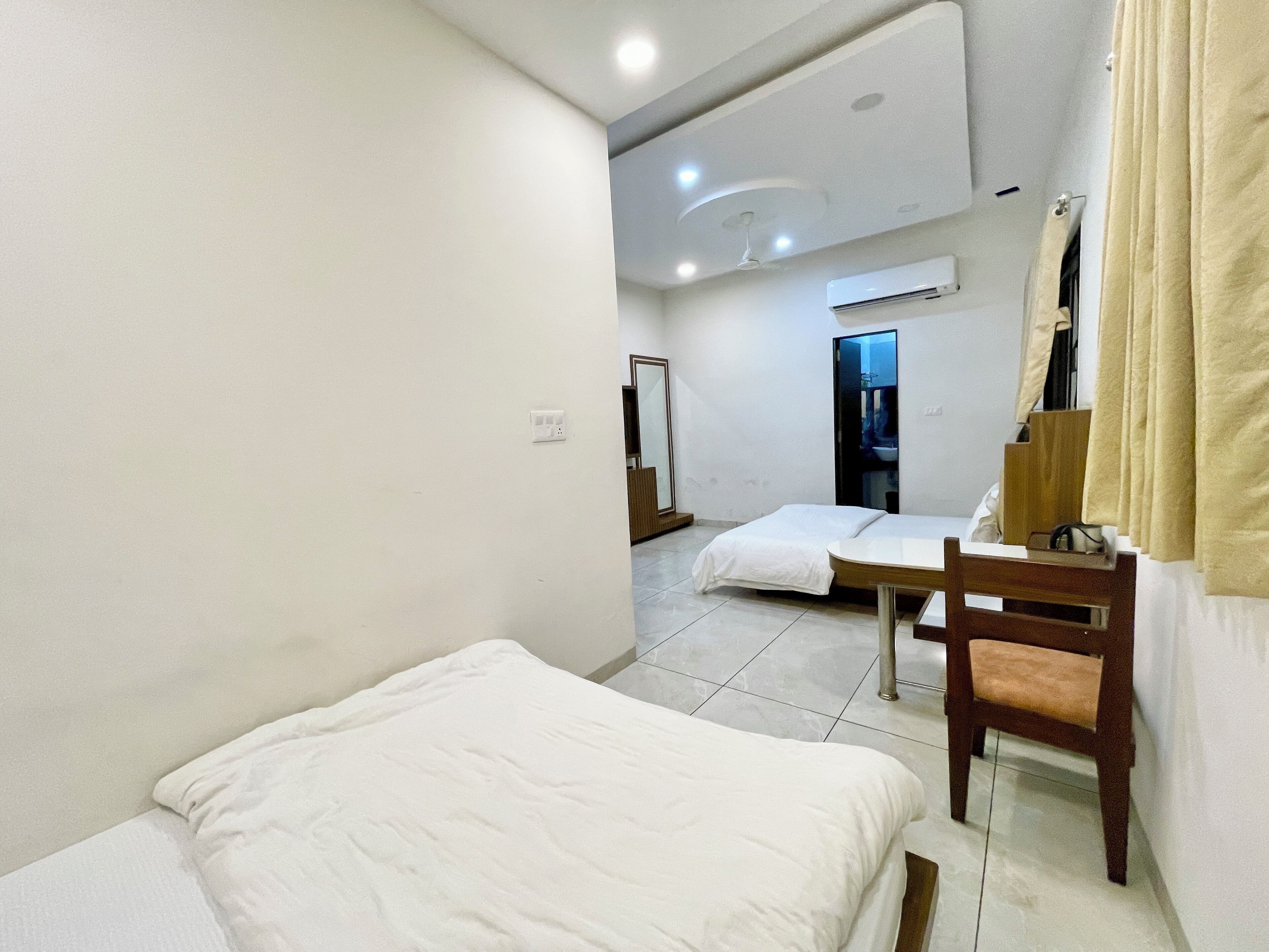 A hotel room with a bed, a chair, a desk, and a mirror.