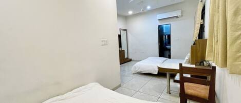 A hotel room with a bed, a chair, a desk, and a mirror.