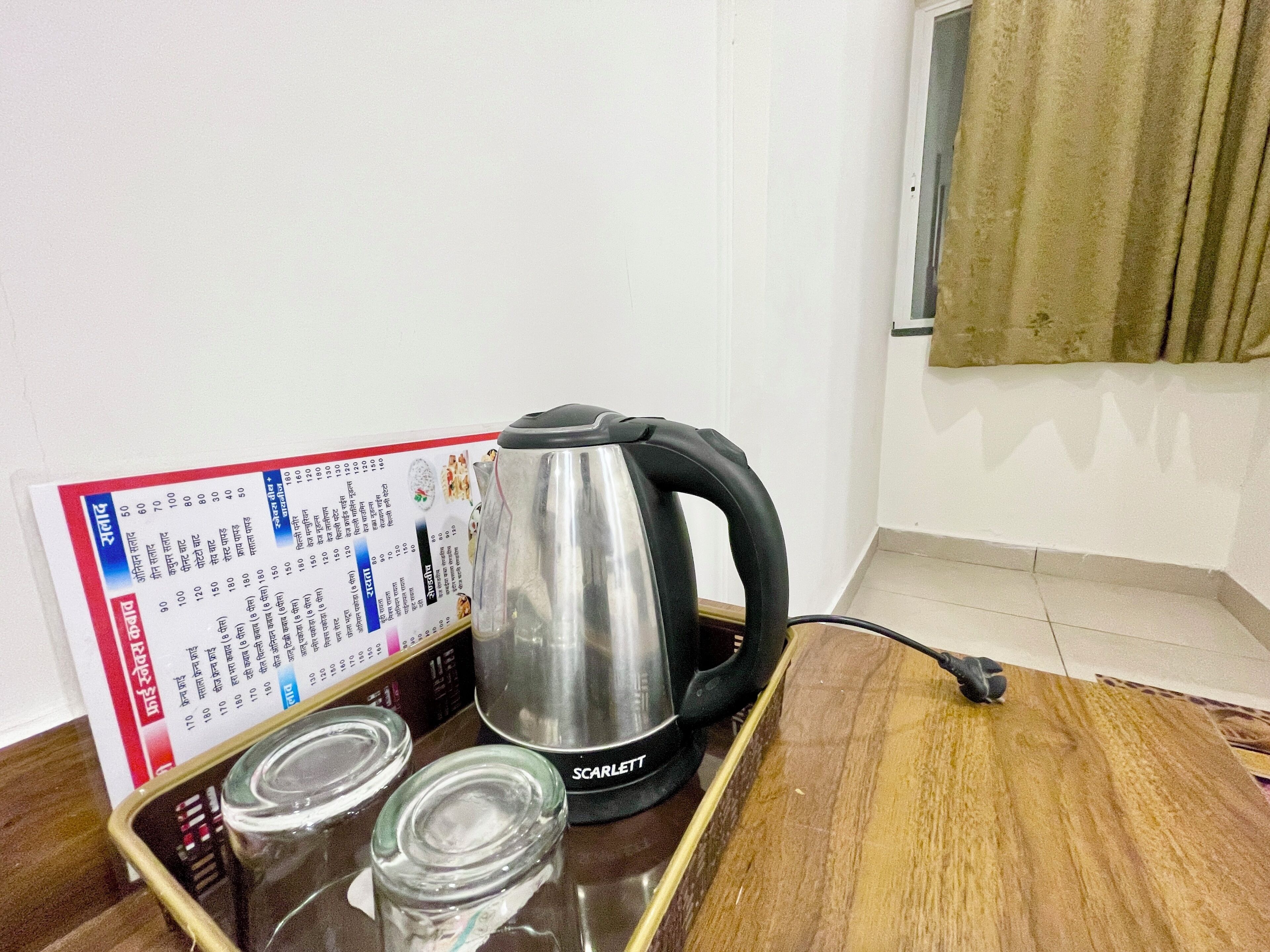 A kitchen area with a kettle, a tray, and a menu board.