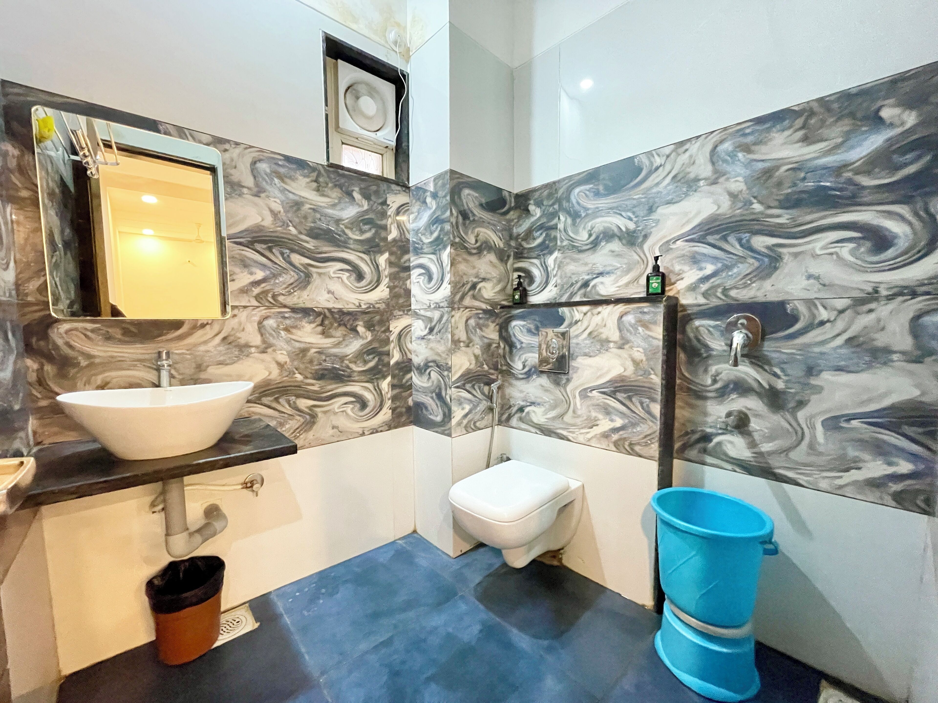 A bathroom with a white sink, a toilet, and a blue bucket.