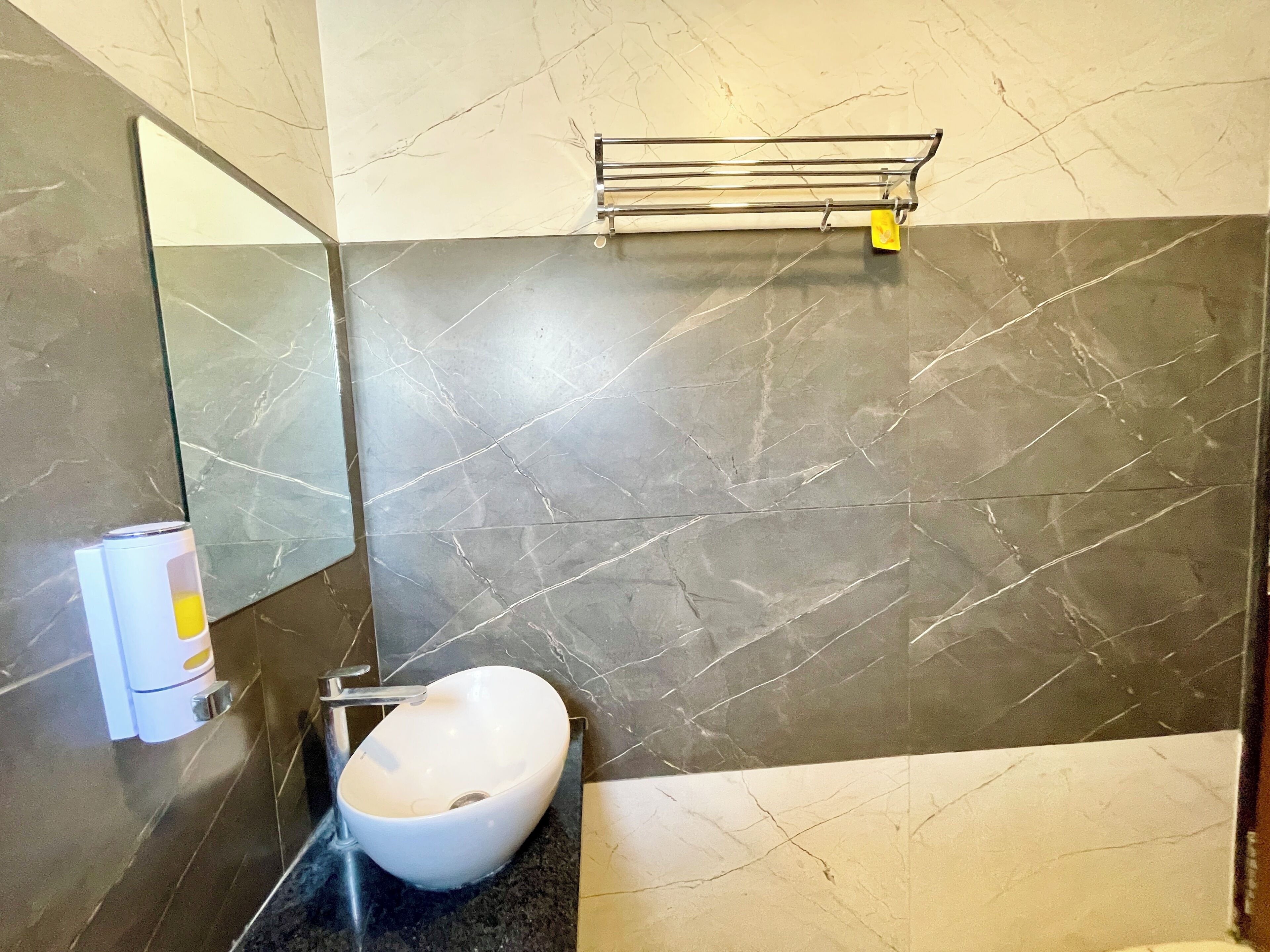 A bathroom with a white sink, dark marble walls, and a mirror.