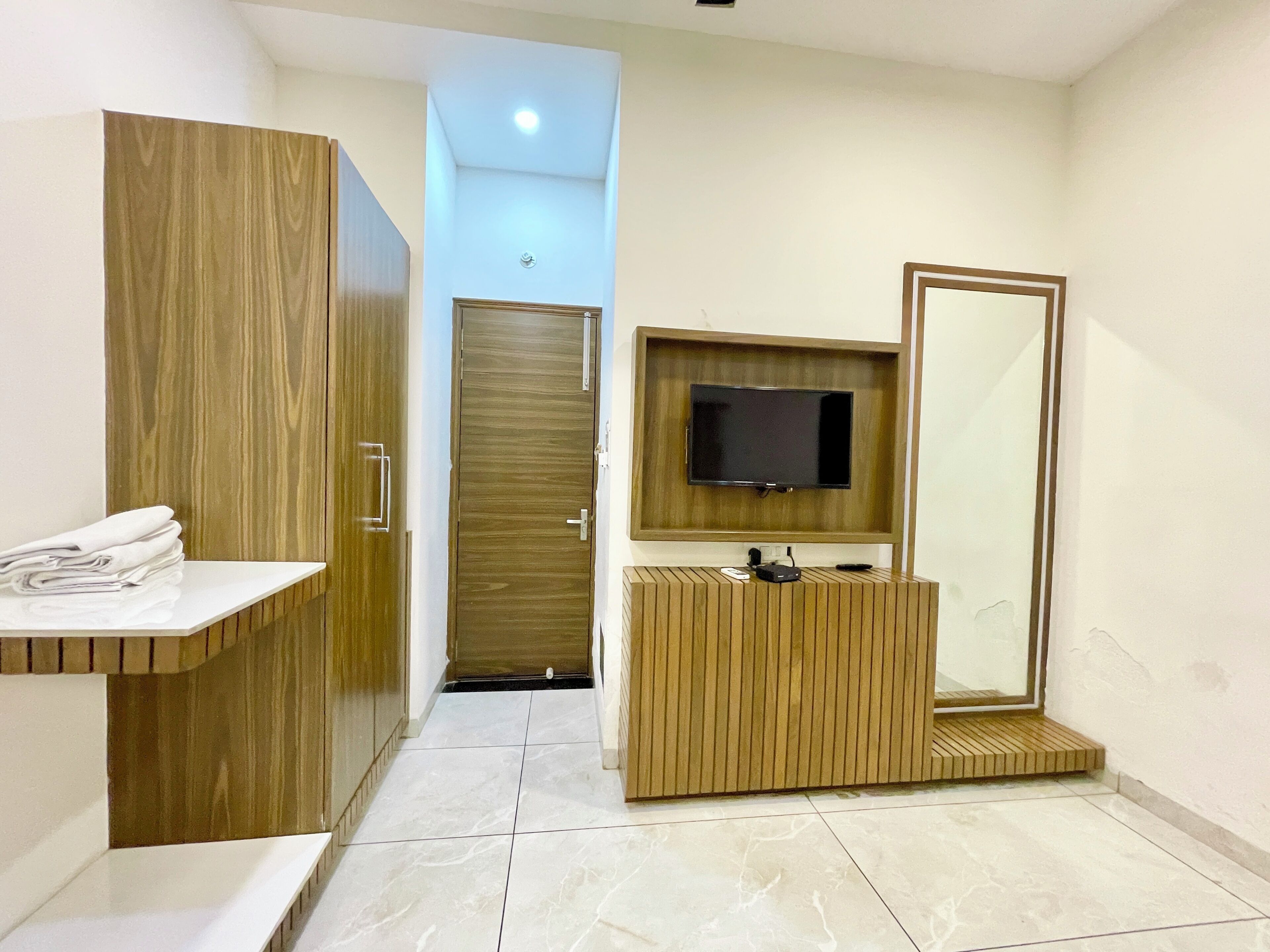 Une salle de bain moderne avec un meuble-lavabo en bois, un miroir et un téléviseur fixé au mur.