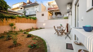 Une cour comprenant un espace repas, une clôture en bois et un jardin fleuri.