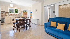 Une cuisine moderne avec un coin repas, un canapé bleu et une vue sur l’extérieur.
