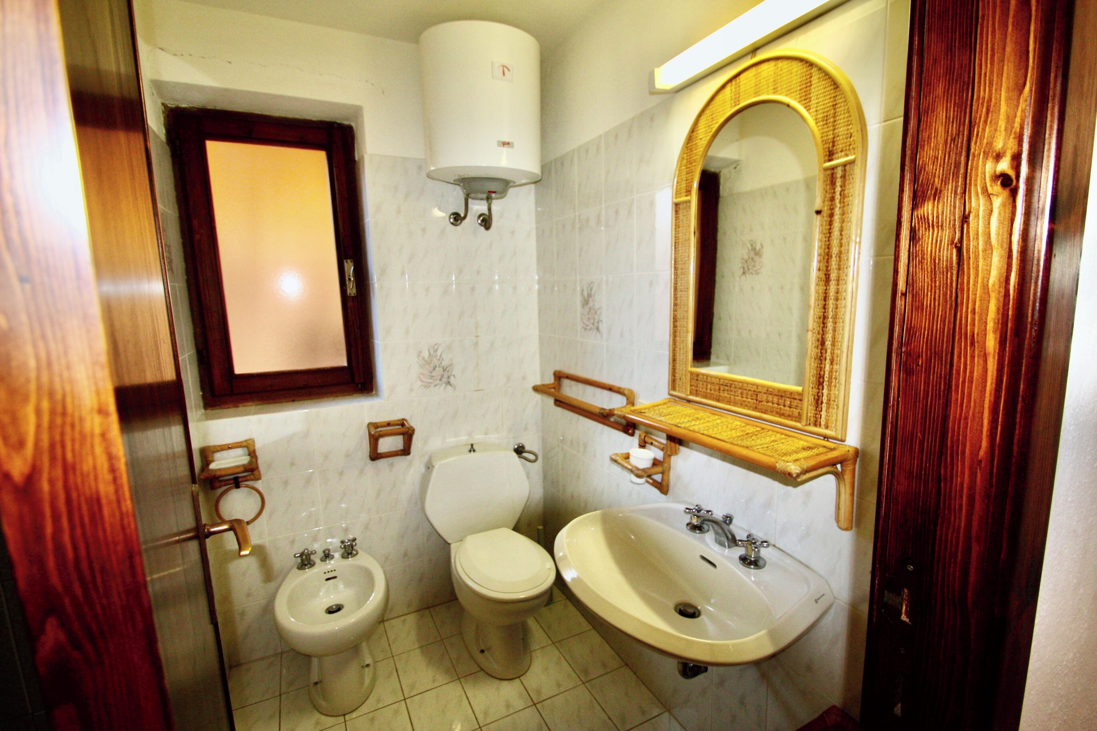 A bathroom with two toilets, a sink, a mirror, and a towel rack.
