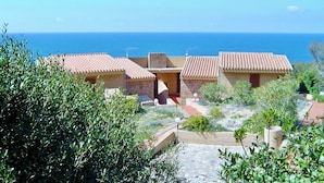 Ein Küsteneigentum mit Gebäuden mit Terrakotta-Dachziegeln, einem Steinweg und Blick auf das Meer.