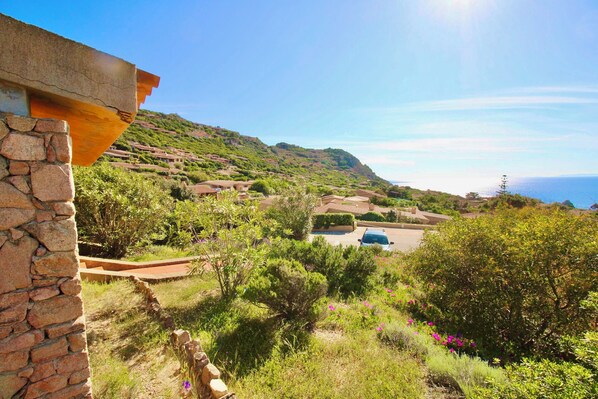 A hillside residential area with stone walls and lush greenery.
