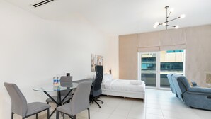 Ein modernes Wohnzimmer mit einem Glastisch, grauen Stühlen, einem weißen Sofa und einem blauen Liegesessel.