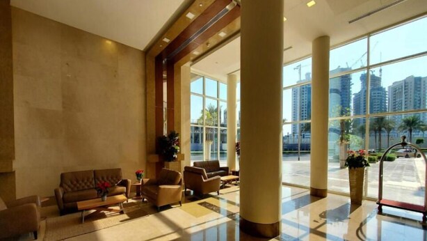 Eine geräumige Lobby mit großzügiger Sitzecke, einer Rezeption und großen Fenstern mit Blick auf die umliegende Stadtlandschaft.