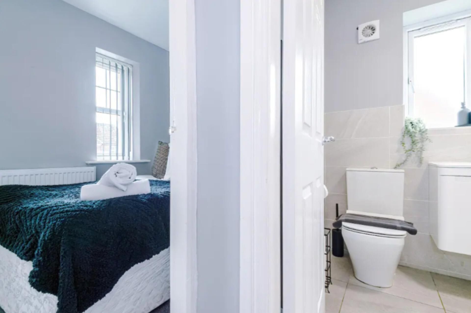 Une chambre avec un lit, une fenêtre, une salle de bain avec des toilettes et un lavabo.