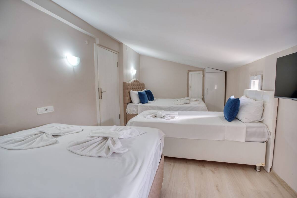 A hotel room with two beds, a large mirror, and a TV mounted on the wall.