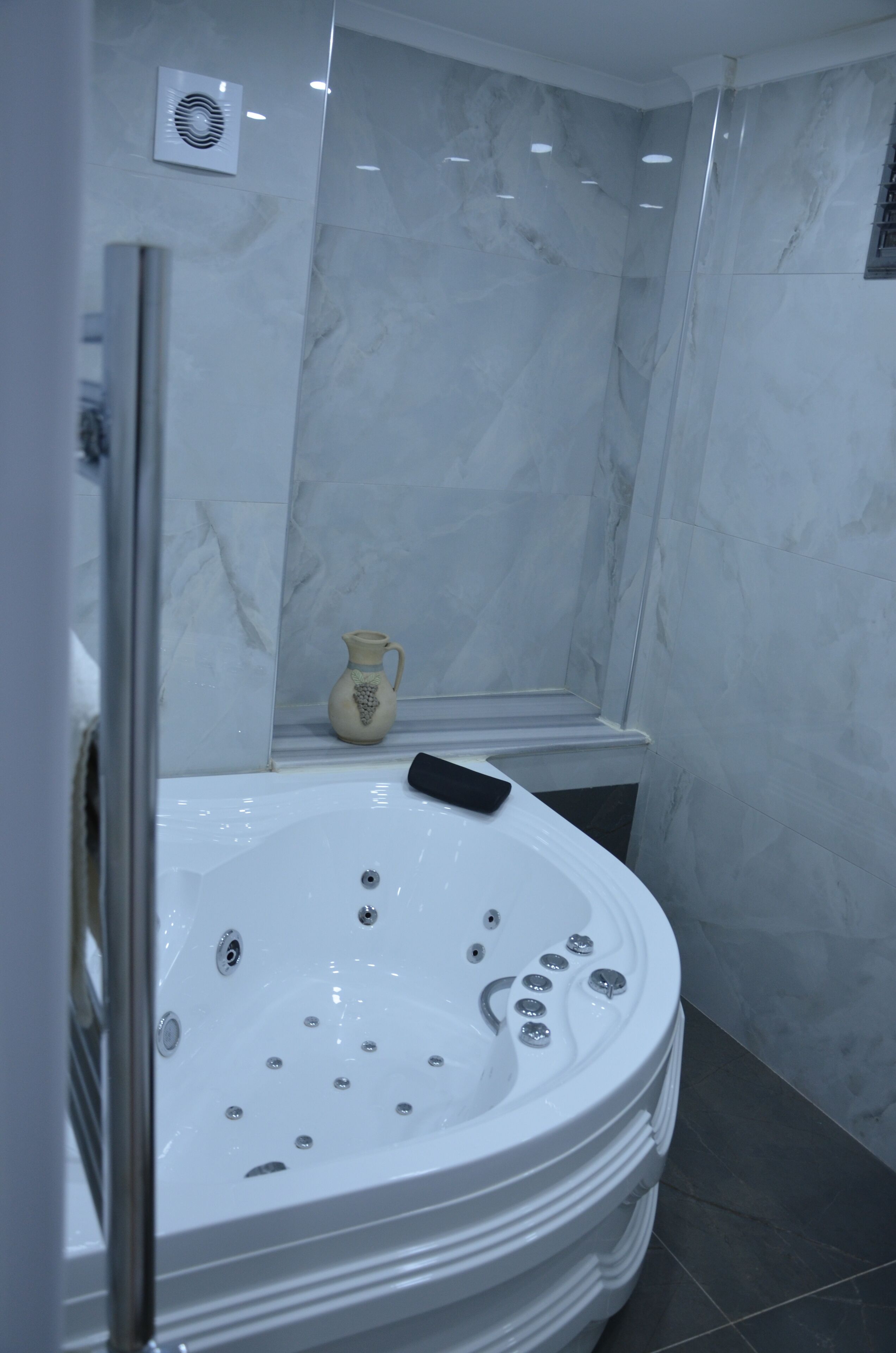 A modern bathroom with a large freestanding bathtub, a small decorative vase, and a built-in shower area.