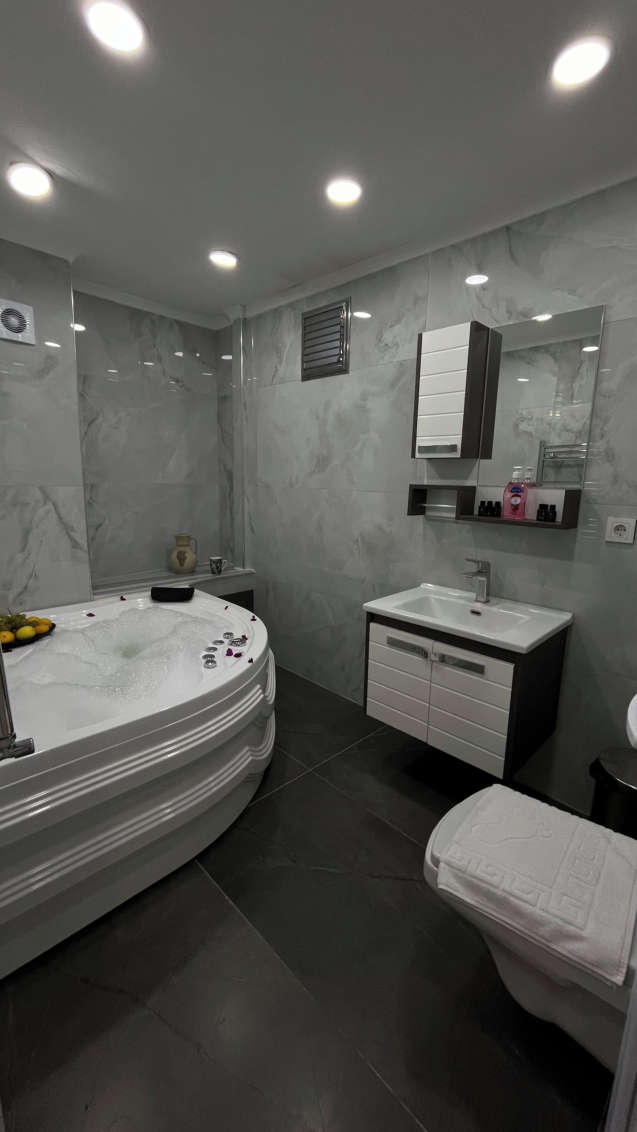 Un baño moderno con una bañera independiente, un tocador con espejo y un inodoro.