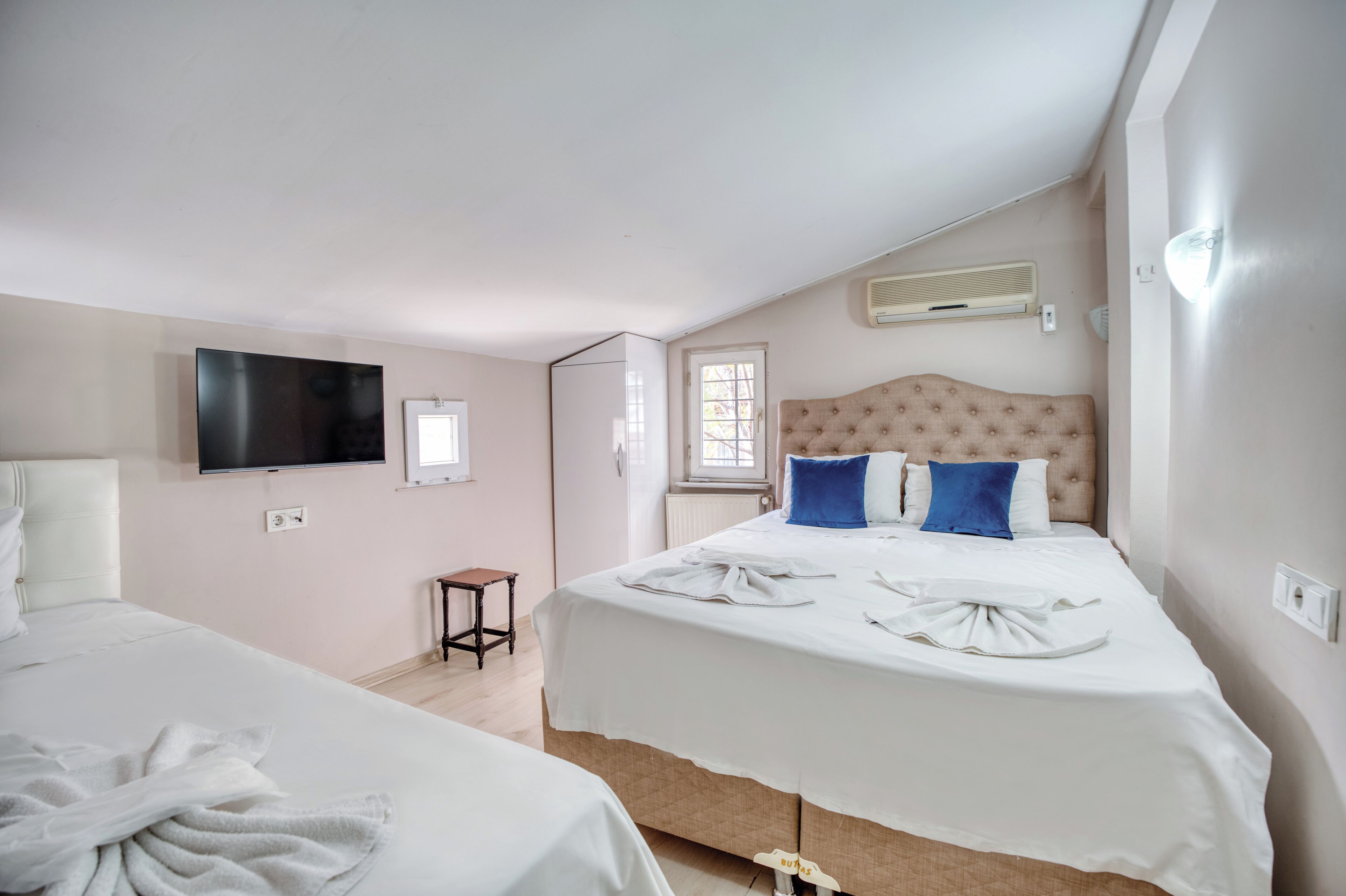 Habitació d'hotel amb dos llits, televisió, finestra i radiador.